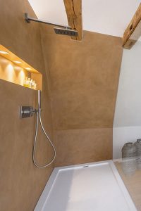 Das Wandelement links nimmt die Installation für die Dusche auf und teilt den Raum in Bad- und Schlafbereich.